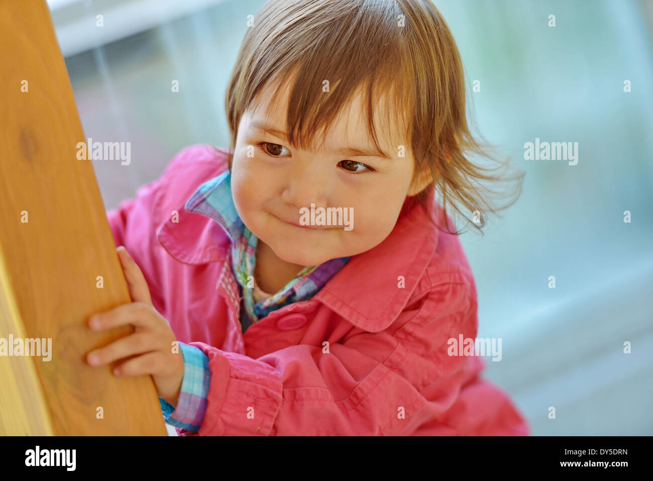 Weiblichen Kleinkind spähen aus einem hölzernen Pfosten Stockfoto