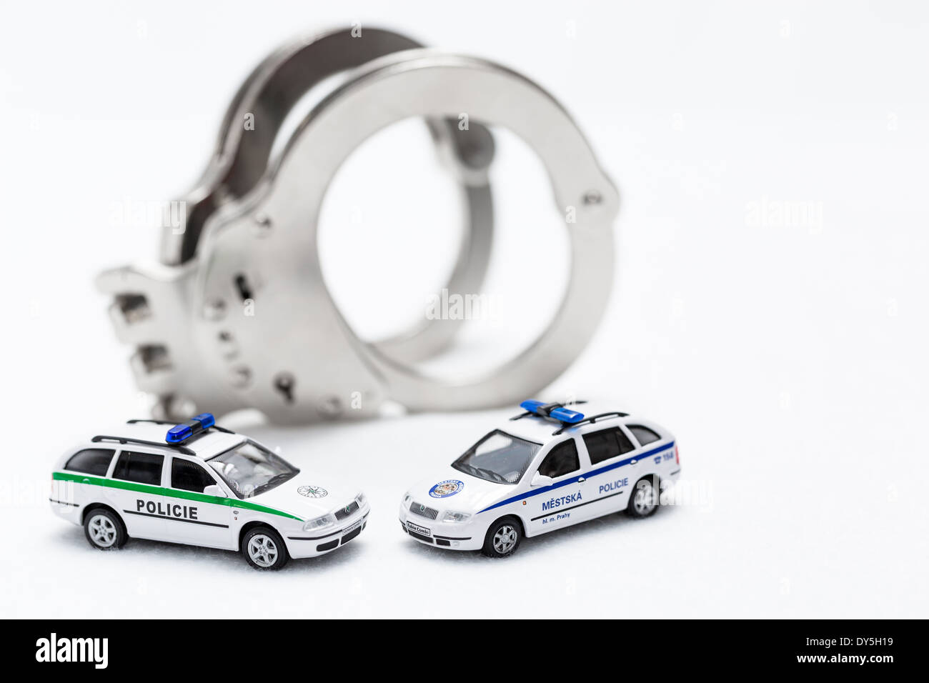 Fesseln mit Modellen von Polizei und Stadt Polizeiauto auf weißem Hintergrund Stockfoto
