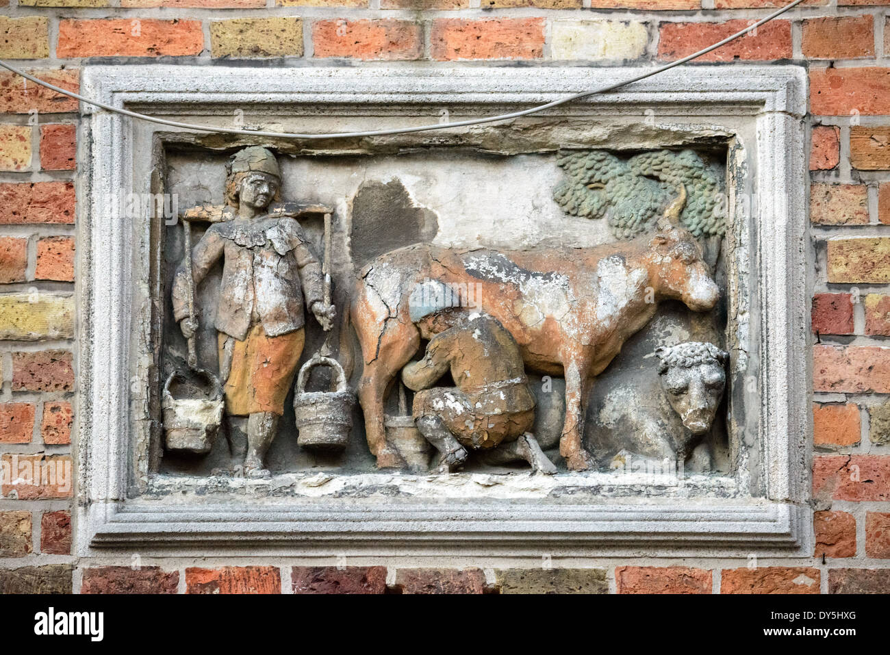 BRÜGGE, Belgien – Ein historischer Steinhaushalt zeigt den ehemaligen Standort eines Milchbetriebs im mittelalterlichen Zentrum von Brügge an. Diese architektonischen Details, die im historischen Viertel üblich sind, dokumentieren die Handelsgeschichte der Stadt. Der erhaltene Marker zeigt, wie mittelalterliche Unternehmen ihre Präsenz in der städtischen Landschaft prägten. Stockfoto