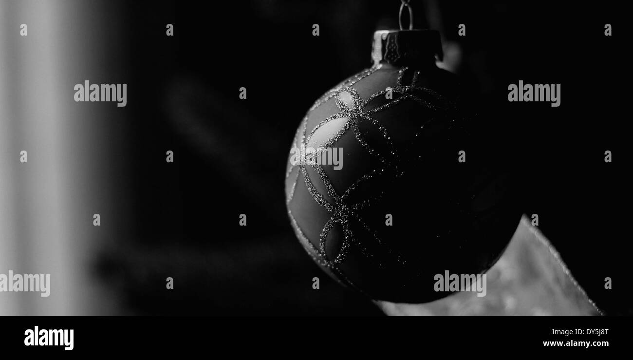 Weiches Licht aus einem nahe gelegenen Fenster wirft Licht auf ein Schmuckstück von einem Weihnachtsbaum hängen. Stockfoto