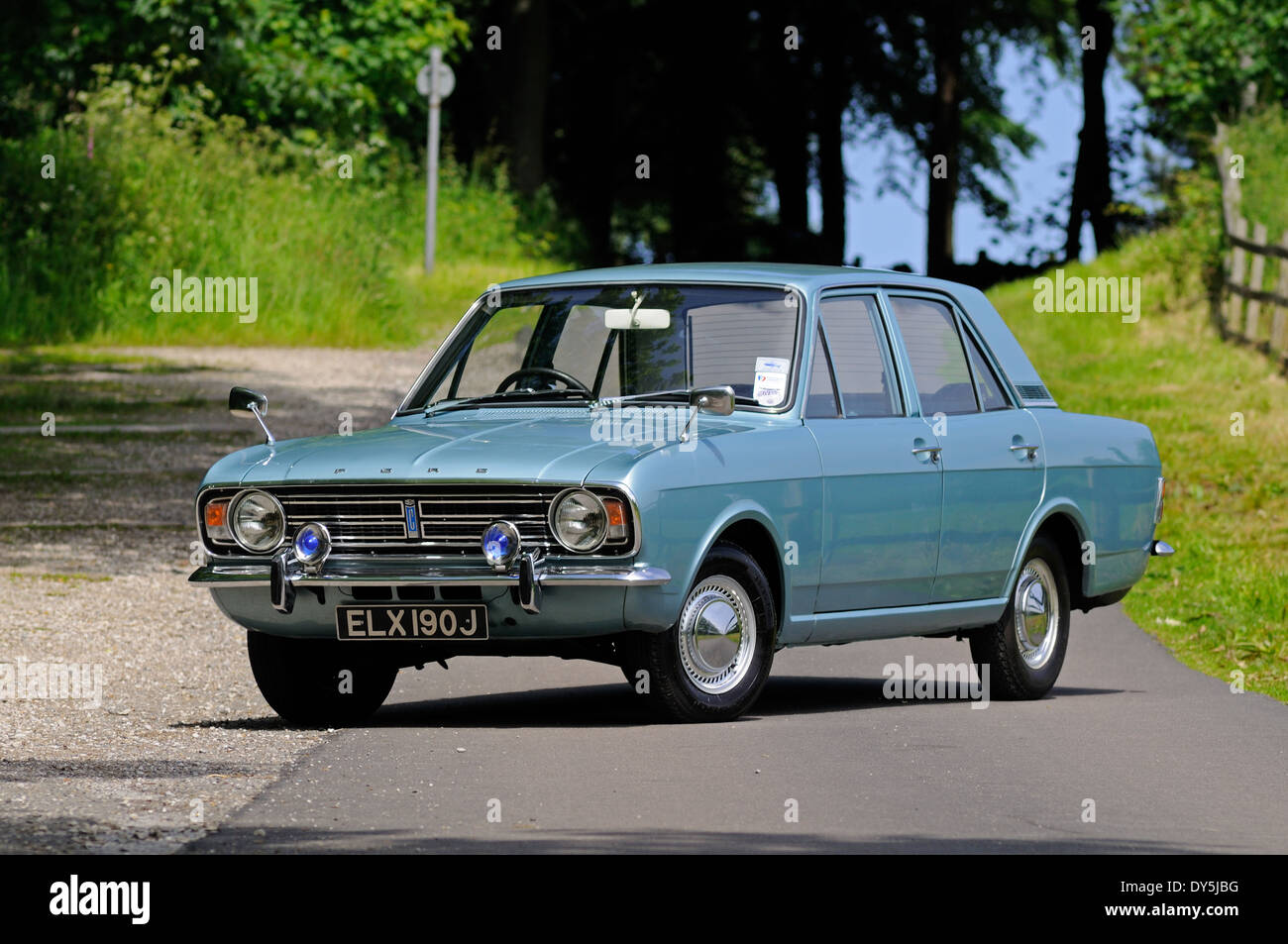 Ford Cortina MkI steht in der Sonne einen englischen Country Lane mit Wald hinter Stockfoto