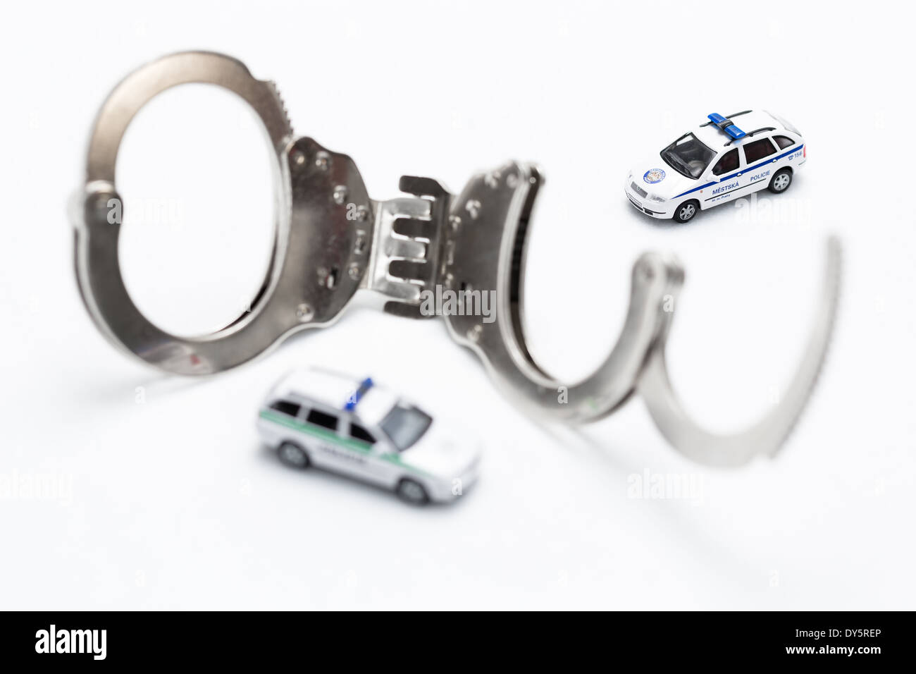 Fesseln mit Modellen von Polizei und Stadt Polizeiauto auf weißem Hintergrund Stockfoto