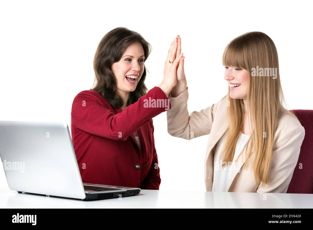 Zwei glückliche Frauen blond und brünett, sitzen zusammen vor einem laptop Stockfoto