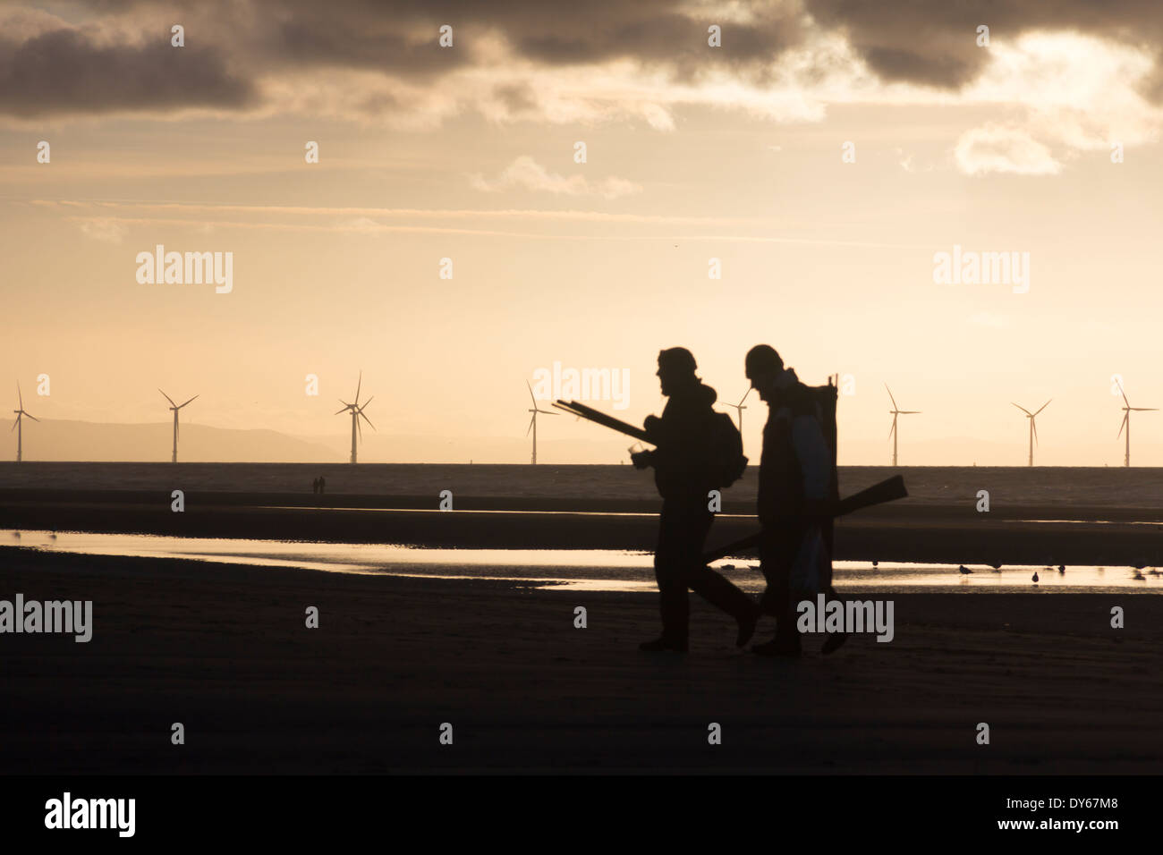 Zwei Silhouette Meeresangler zum Strand von Formby Punkt Liverpool Bay mit der Offshore-Windpark Burbo Bank im Hintergrund. Stockfoto