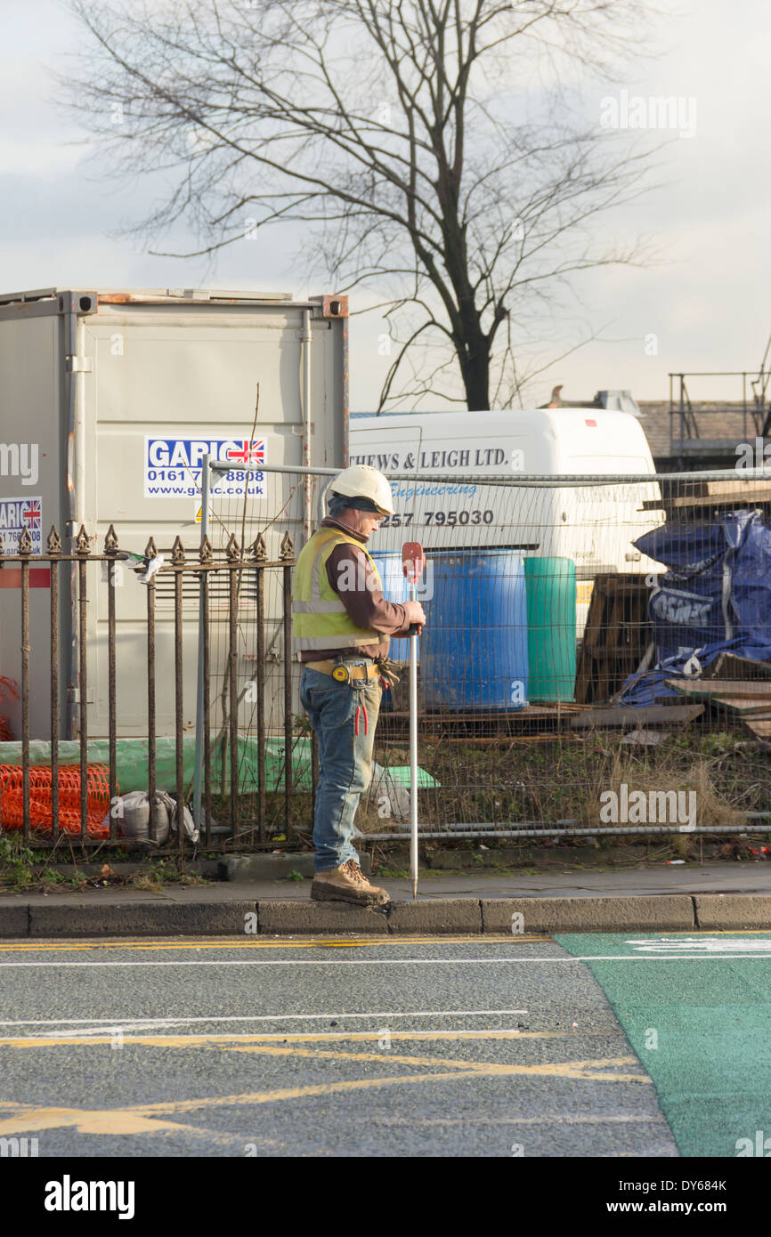 Die Bauarbeiten Landvermesser mit einer Rute Stadien oder Nivellierung Stab im Rahmen einer Vermessung arbeiten auf einer Baustelle in England. Stockfoto