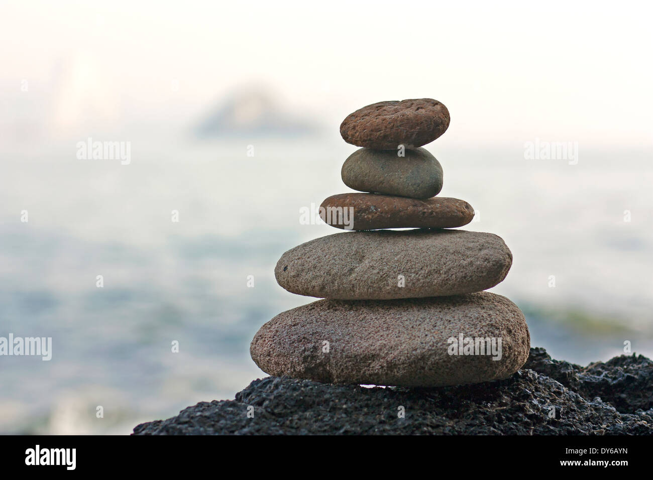 Steinen Pyramide auf Sand als Symbol für Zen, Harmonie und Balance. Ozean im Hintergrund Stockfoto