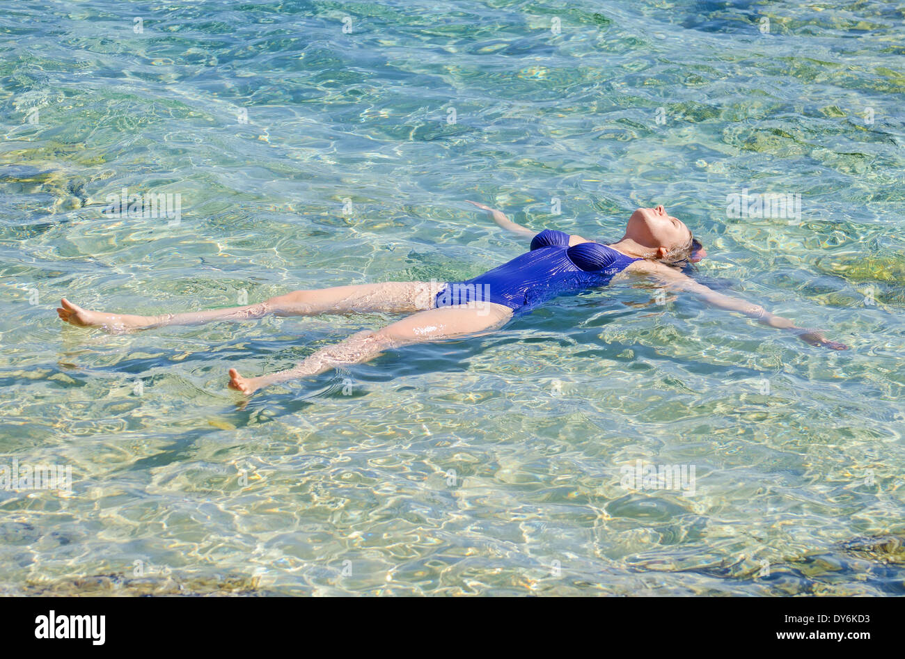 Hübsche Frau im transparenten türkisfarbenen Meer zu schwimmen. Stockfoto