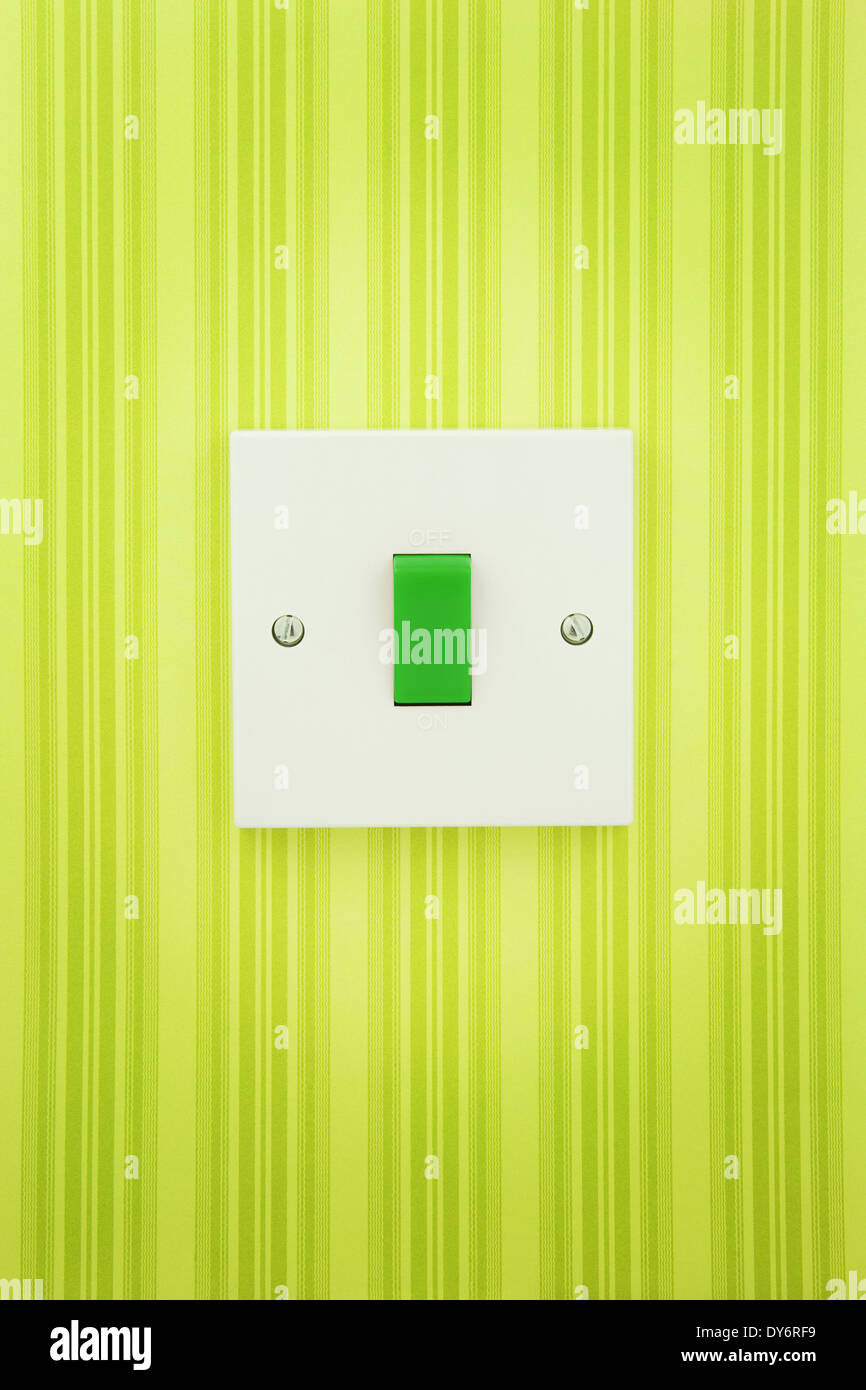 Grün-Schalter auf einem weißen Sockel mit einem gestreiften Wand Papierhintergrund Stockfoto