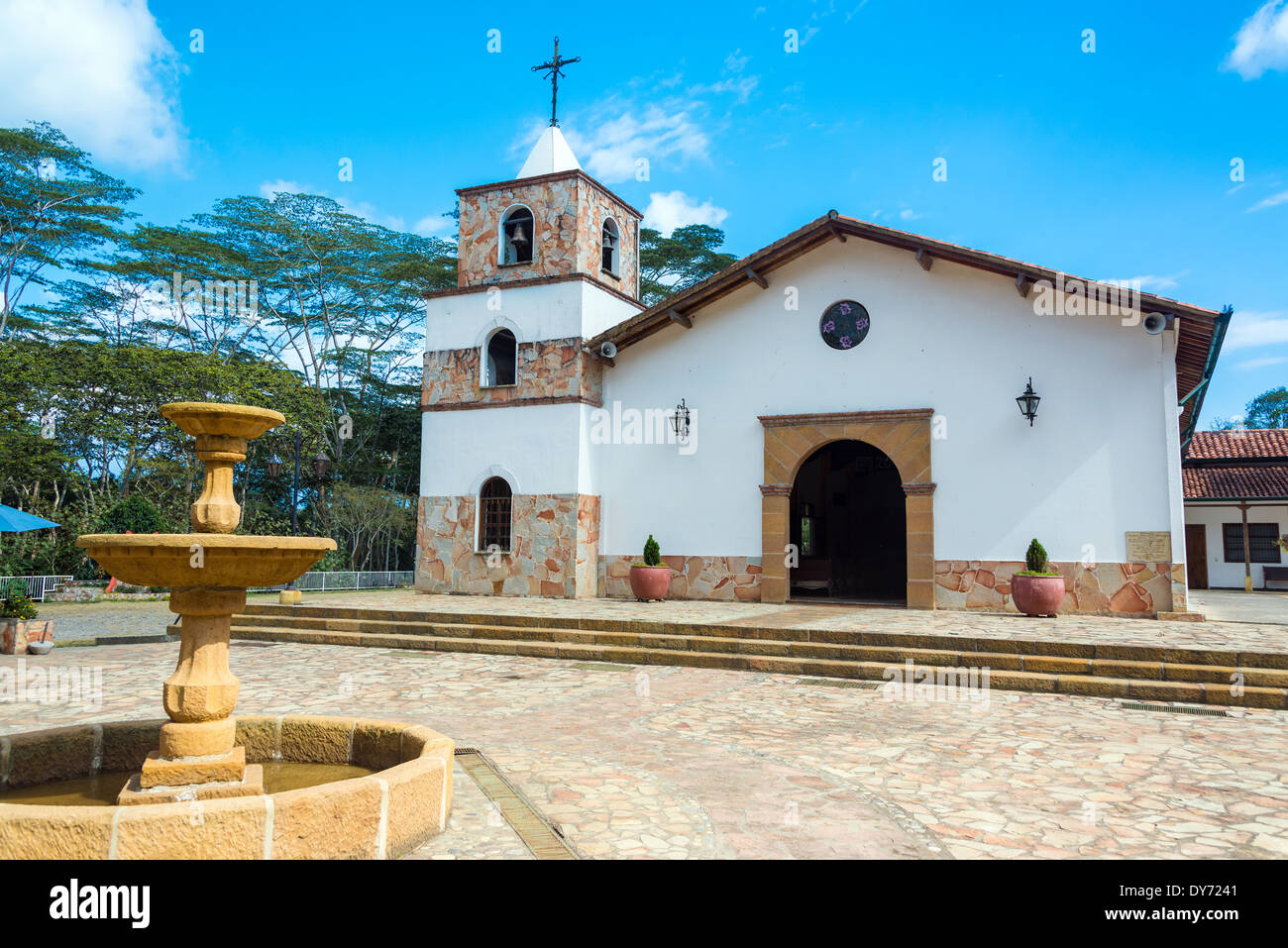 Schöne weiße Kirche in Mesa de Los Santos in Santander, Kolumbien mit einem Brunnen im Vordergrund Stockfoto