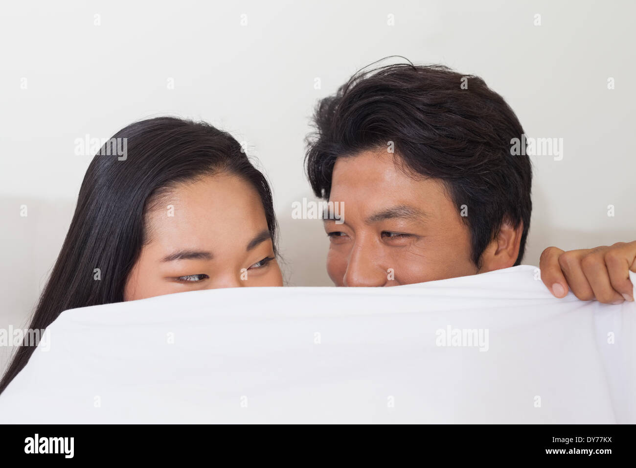 Glückliches Paar Holding Bettdecke über Gesicht Stockfoto