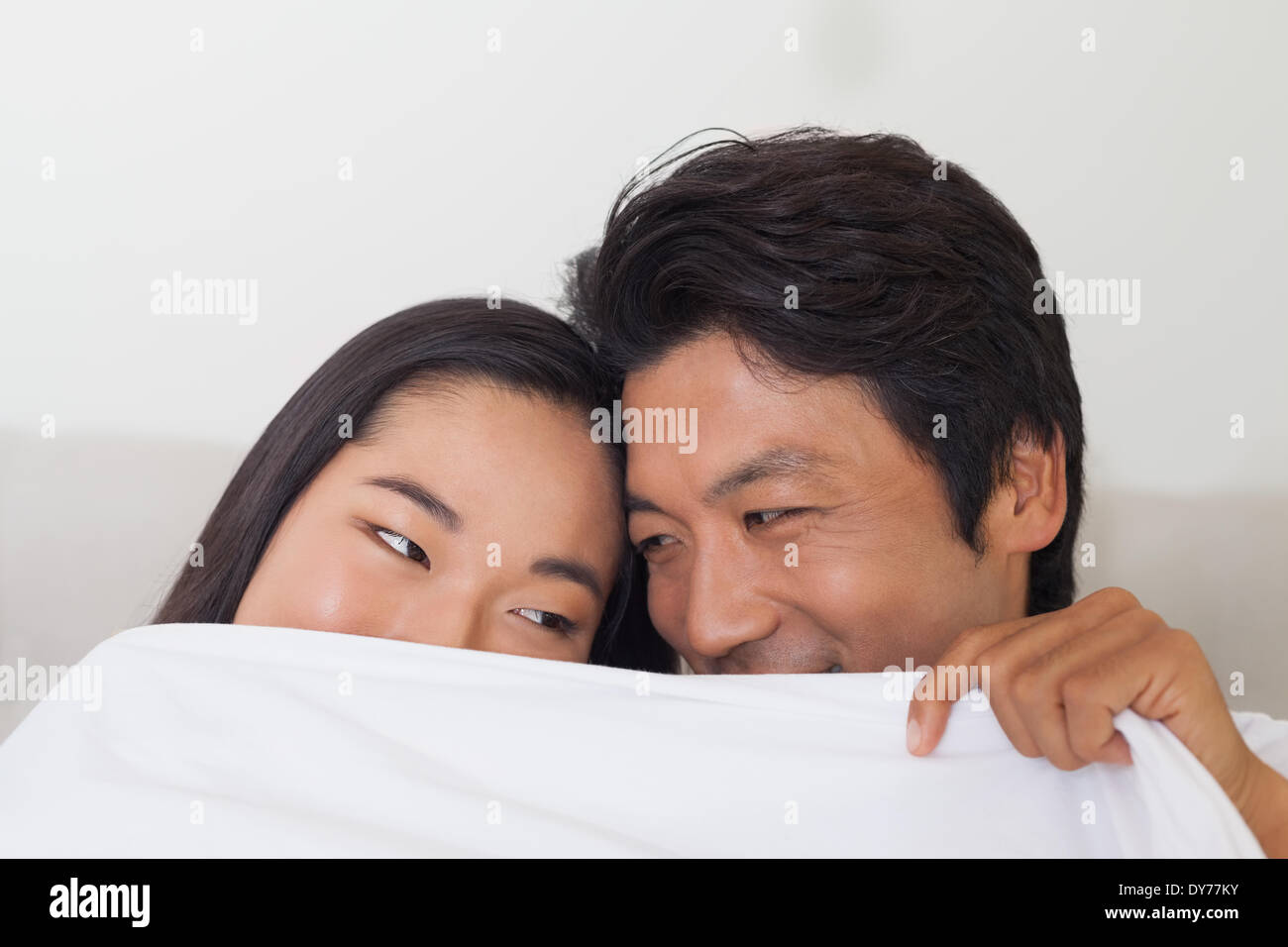 Glückliches Paar Holding Bettdecke über Gesicht Stockfoto