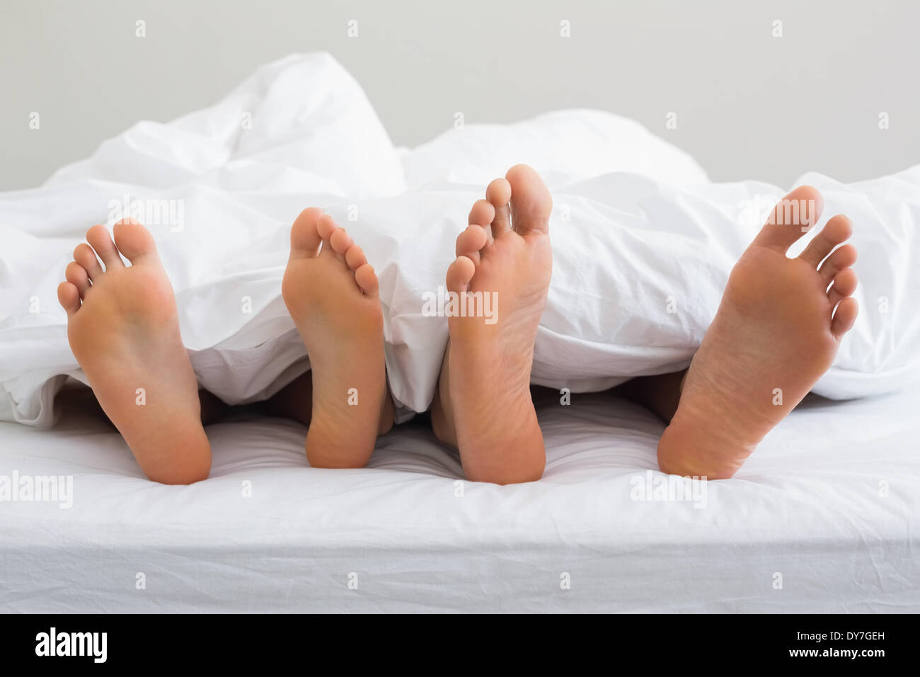Paare-Füße unter der Bettdecke herausstrecken Stockfoto
