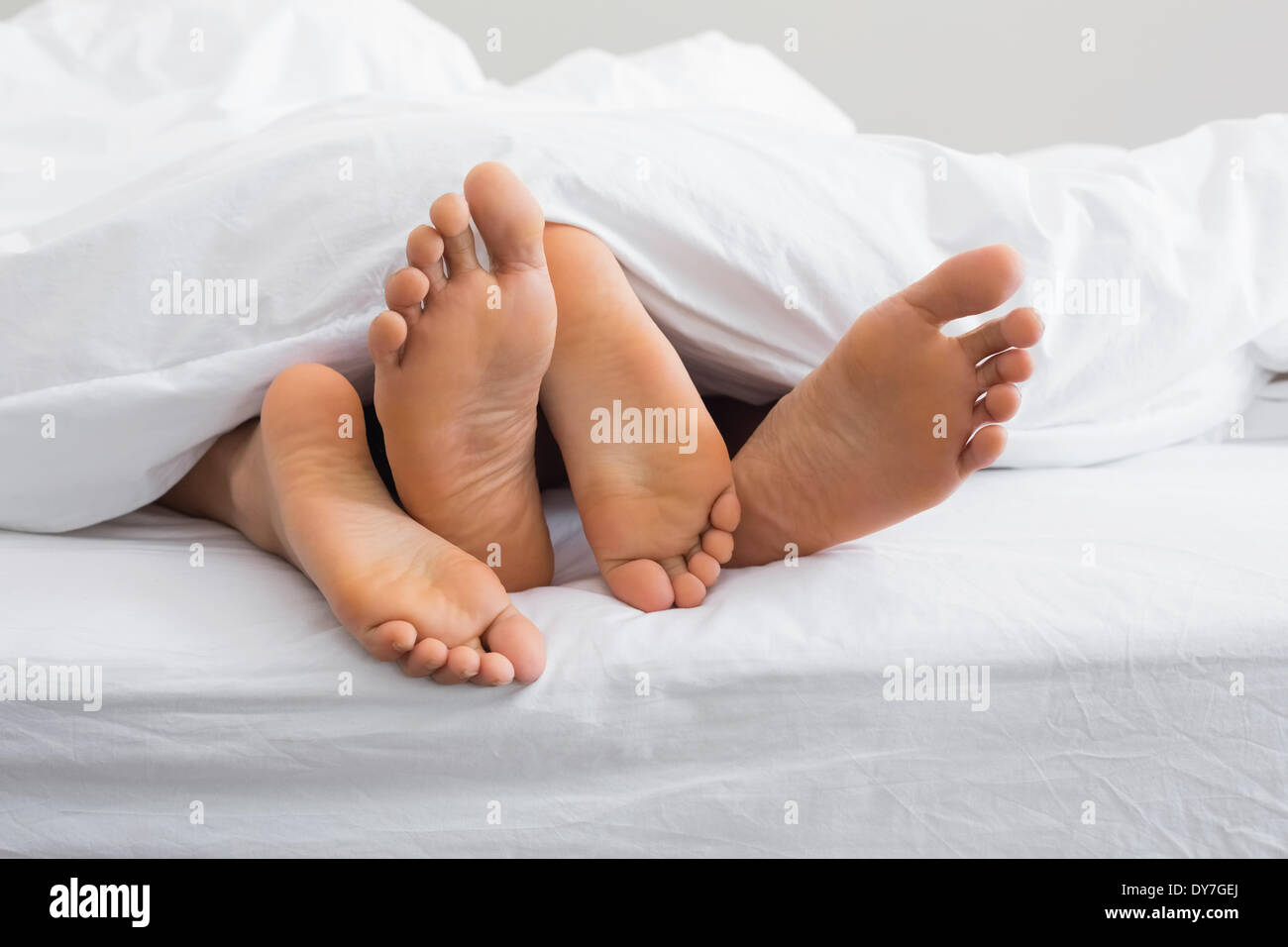 Paare-Füße unter der Bettdecke herausstrecken Stockfoto