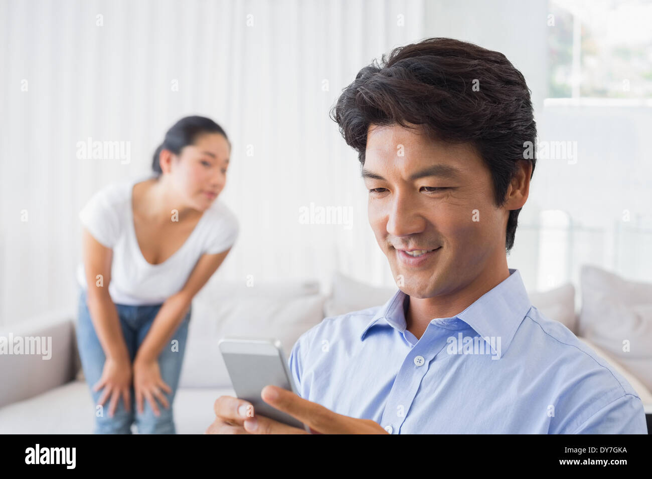 Mann eine SMS senden, während Freundin von Couch Uhren Stockfoto