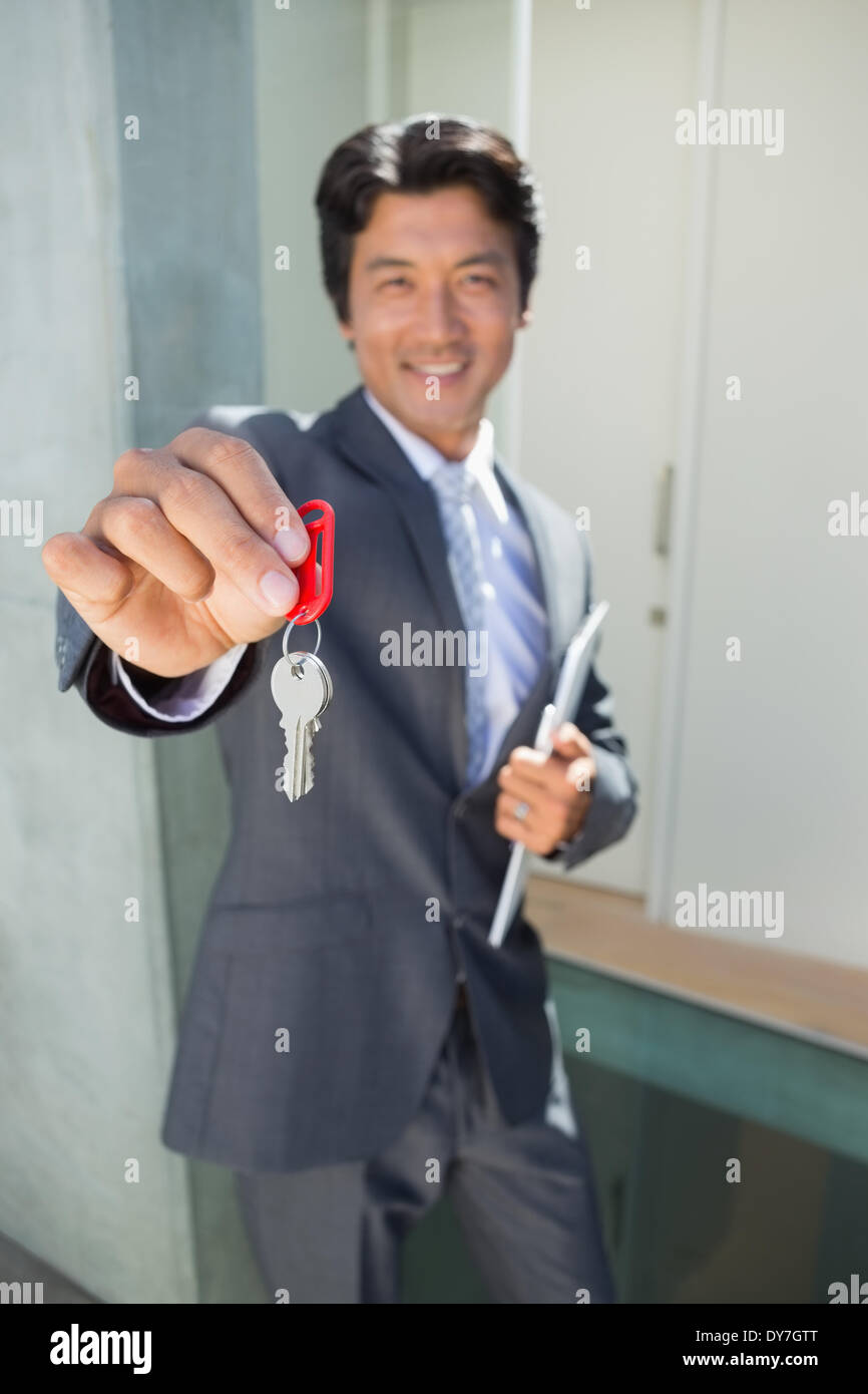 Zuversichtlich zeigt Haustürschlüssel stehenden Immobilienmakler Stockfoto