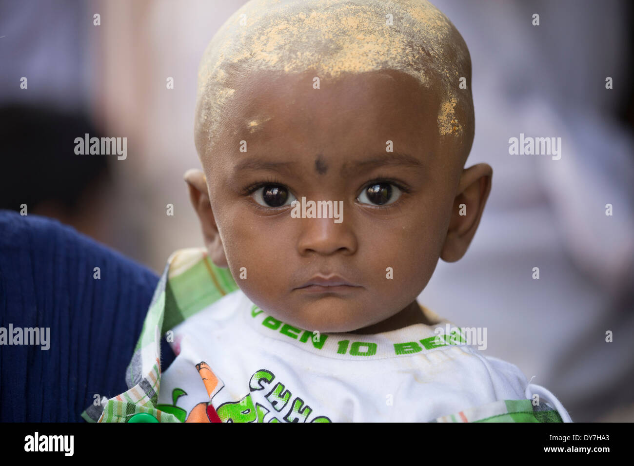 Baby mit Kopf bedeckt in Sandelholz Pulver, während Chithirai Thiruvizha hinduistische Festivals, Madurai, Indien Stockfoto
