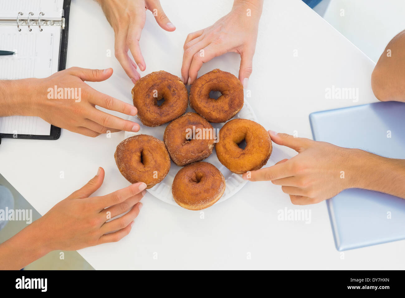 Business-Team erreichte für Donuts auf Tisch Stockfoto