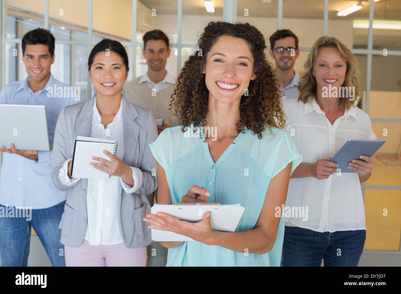 Lässige Chef steht vor ihrem Team alle Notizen in die Kamera Lächeln Stockfoto