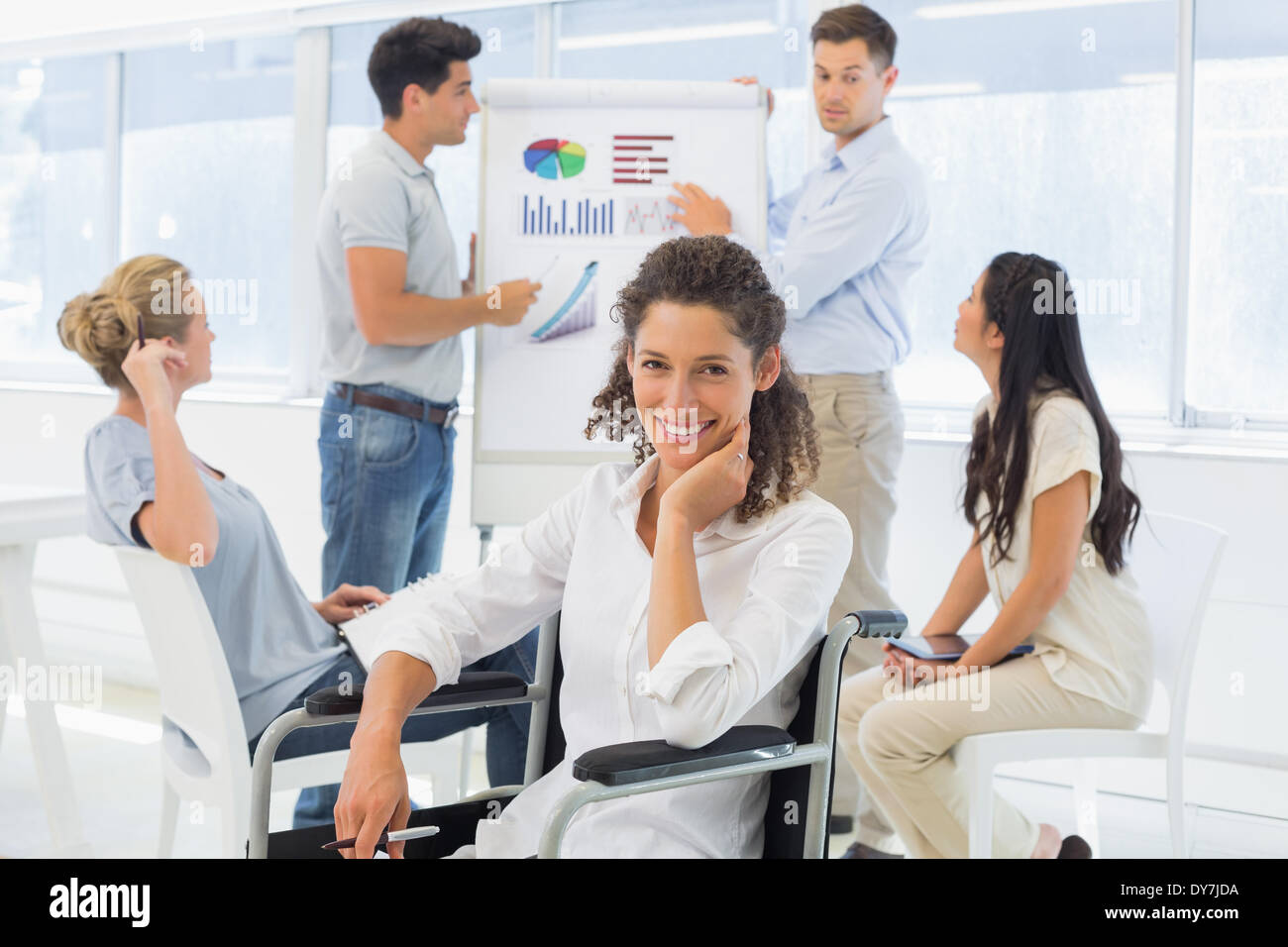 Lässige Geschäftsfrau im Rollstuhl lächelnd in die Kamera während der Präsentation Stockfoto