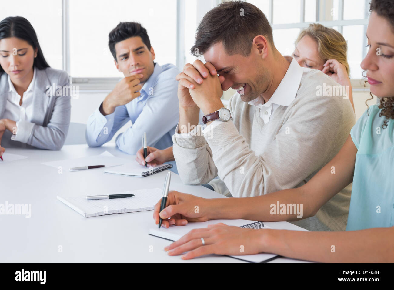 Lässige Geschäftsmann versucht nicht zu lachen während der Sitzung Stockfoto