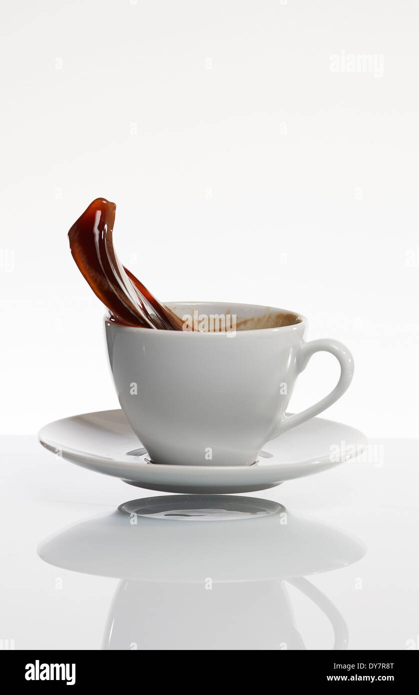 Schwarzer Kaffee spritzt aus weißen Kaffeetasse vor weißem Hintergrund Stockfoto