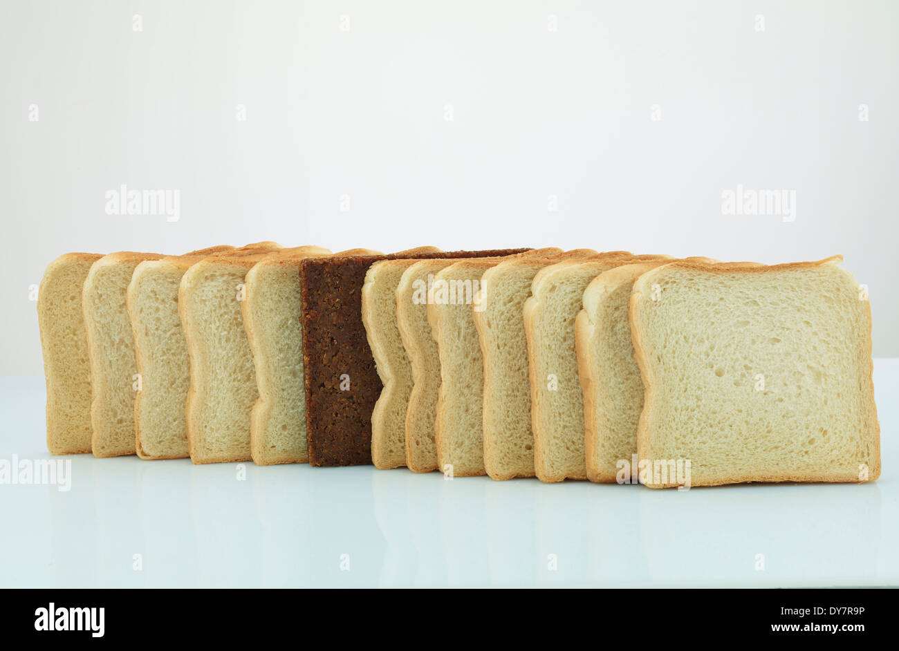 Scheibe Schwarzbrot in einer Reihe von Toast-Brot Stockfoto
