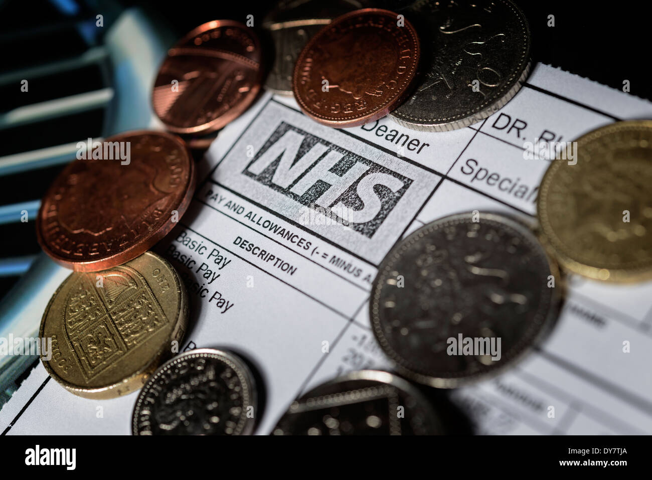NHS bezahlen Zurückhaltung Konzept - eines Arztes NHS Gehaltsabrechnung mit Münzen auf ein medizinisches Lehrbuch. Zahlen und Vertrag Gespräche. Stockfoto