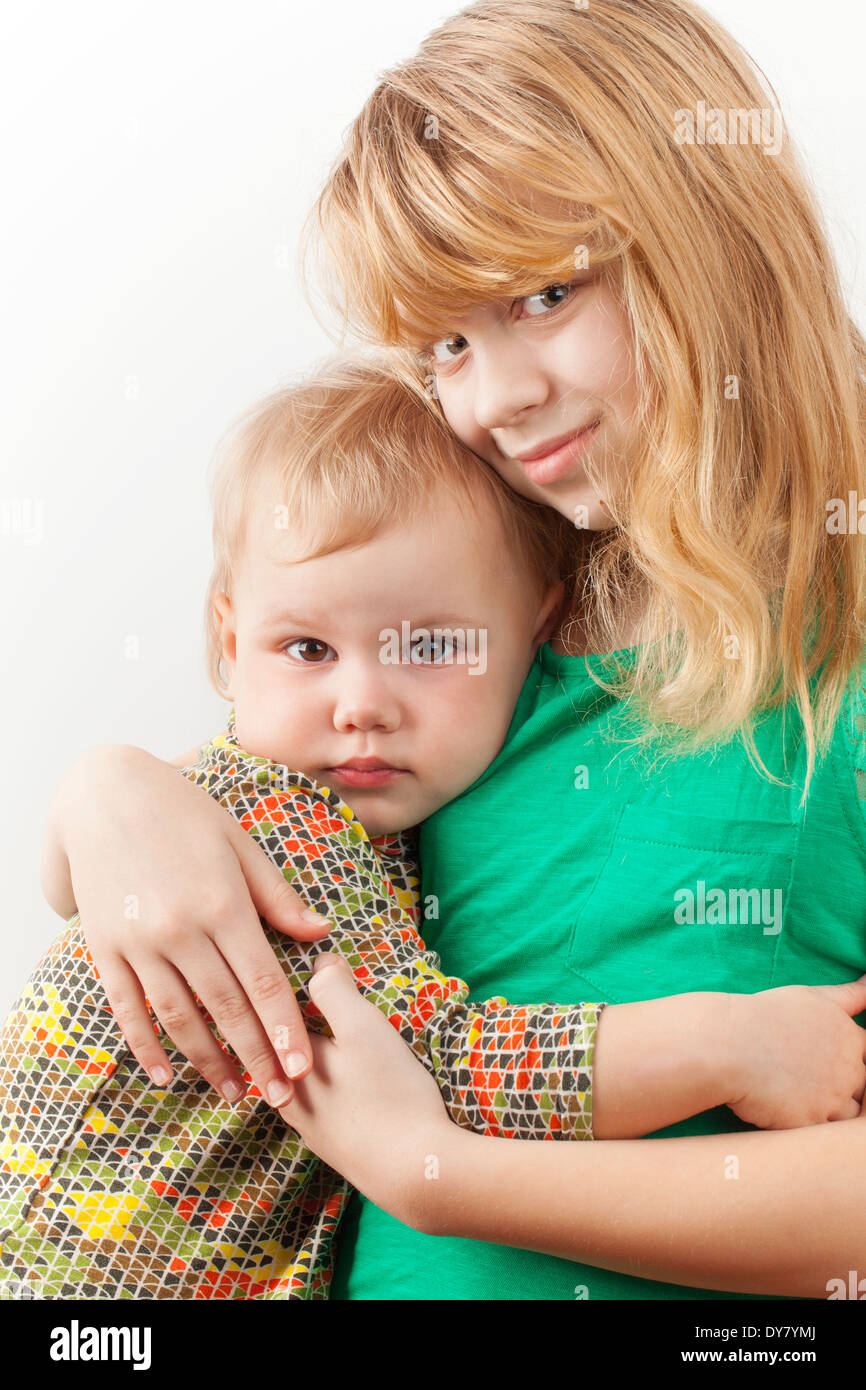 Kleine blonde kaukasische Schwestern umarmen. Closeup Portrait auf weißem Hintergrund Stockfoto