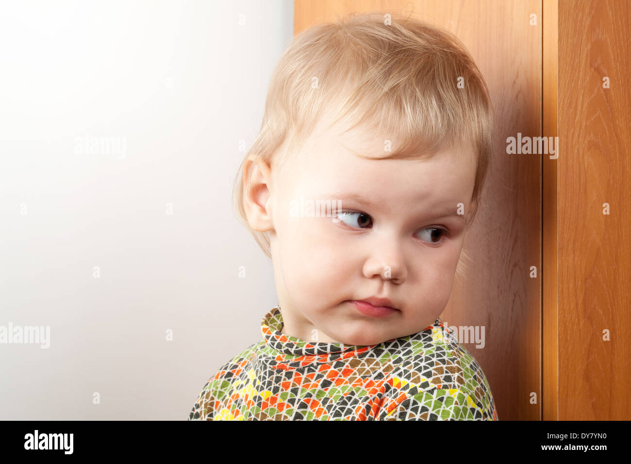 Kleines kaukasische Mädchen versteckt sich hinter einem Schrank Stockfoto
