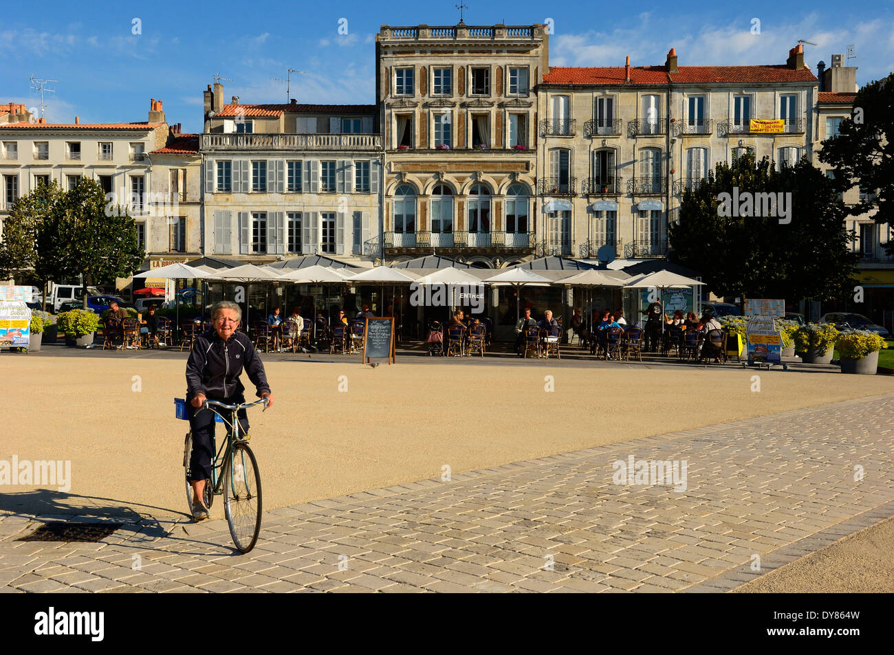 Ein Reife Frau Radfahrer geht Straßencafés. Rochefort. Charente-Maritime Abteilung der Region Poitou-Charentes Frankreich. Stockfoto