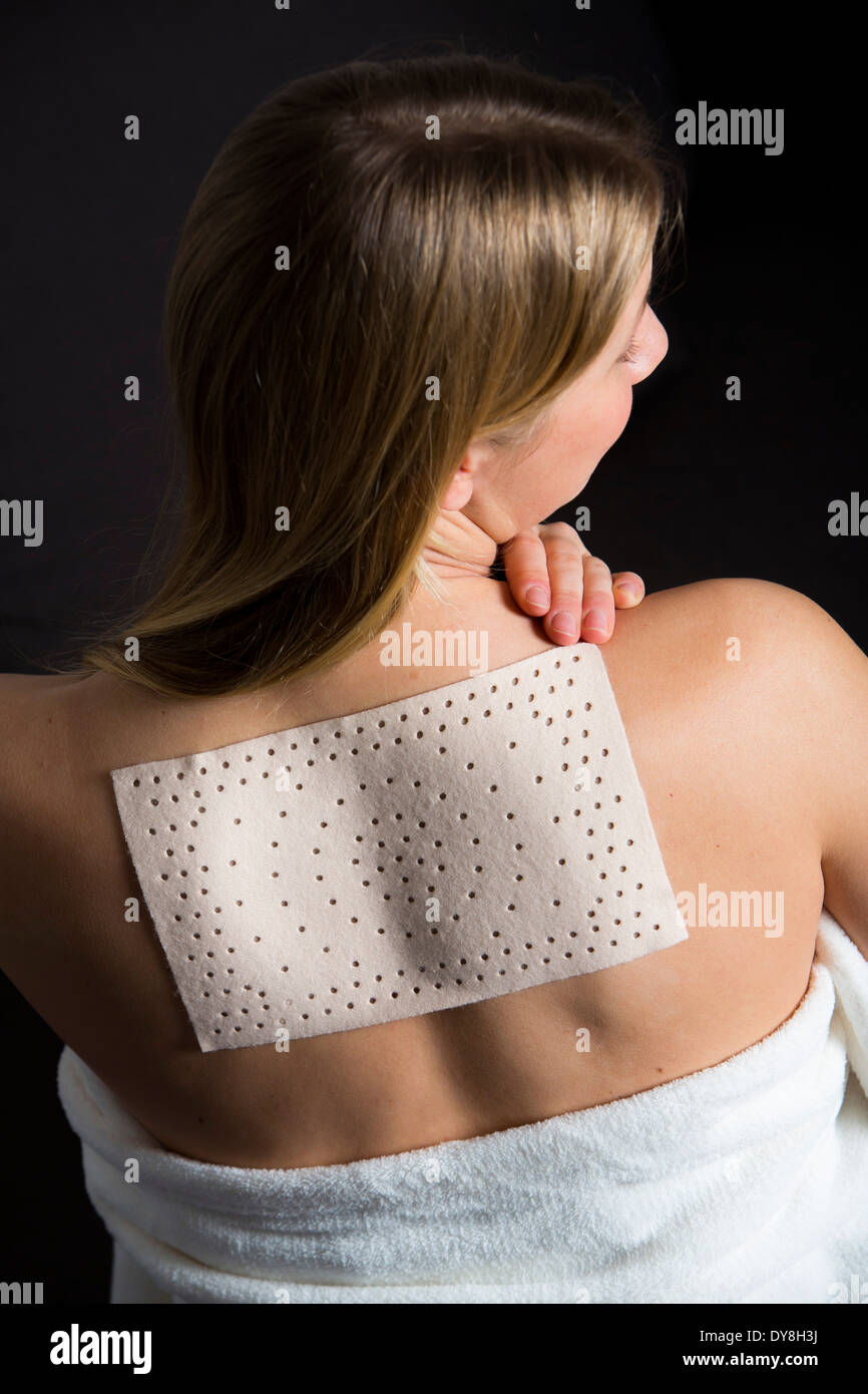 Junge Frau hat Schmerzen im Rücken, tragen ein Wärmepflaster Stockfoto
