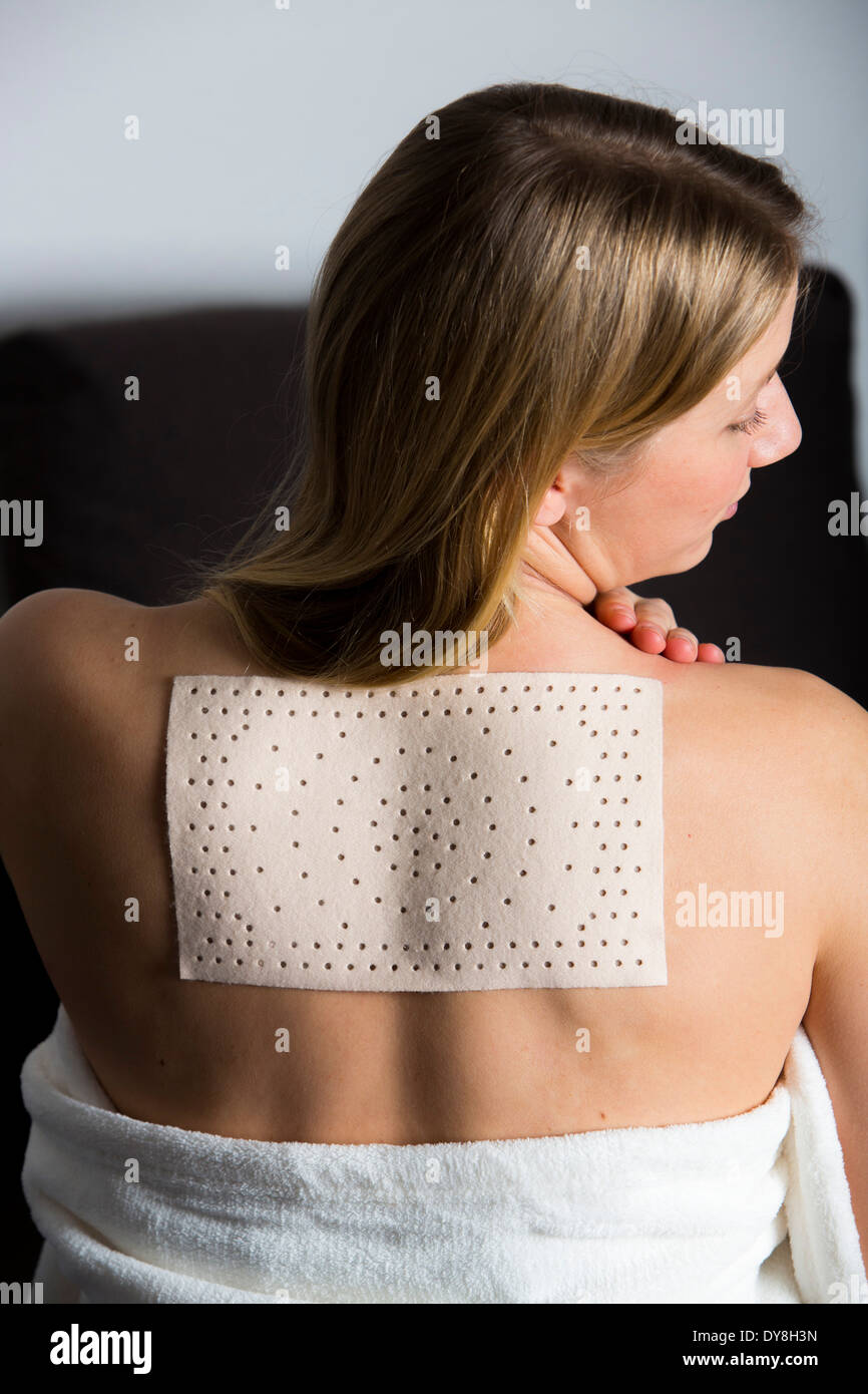Junge Frau hat Schmerzen im Rücken, tragen ein Wärmepflaster Stockfoto