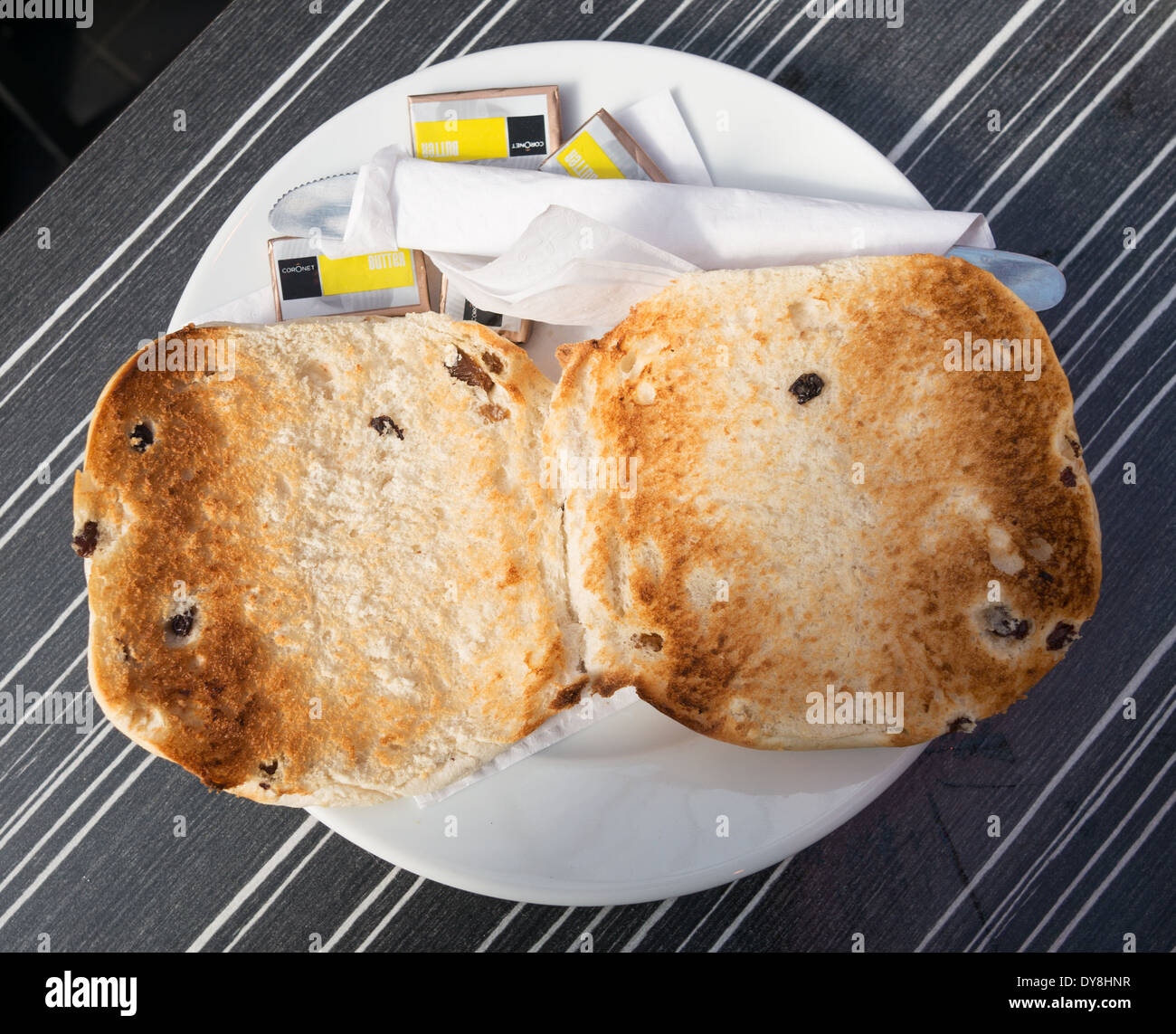 Eine geröstete Teekuchen mit Packungen Butter und Besteck ...
