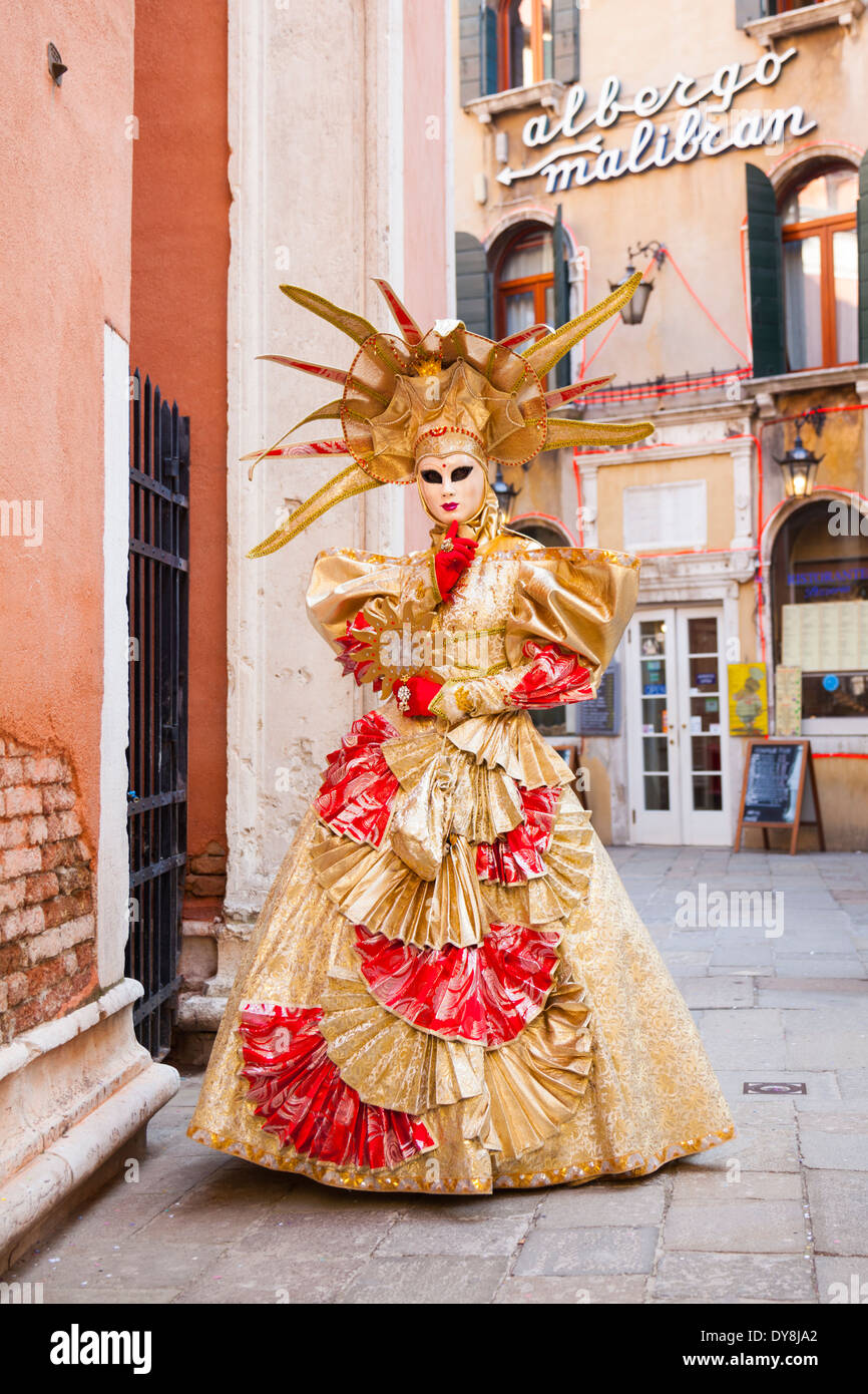 Maskierte Frau im goldenen Ball Kleid Kostüm posiert während des Karnevals in Venedig Stockfoto