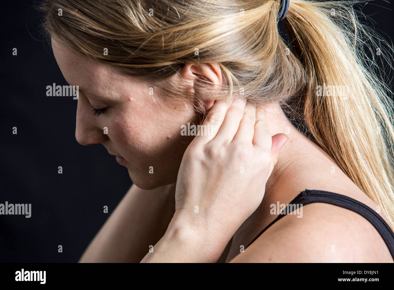 Junge Frau hat Nackenschmerzen, hält seine Halswirbel Stockfoto
