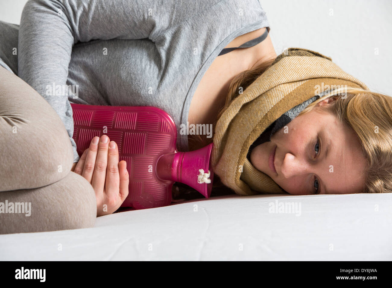 Junge Frau in Schmerzen, lindert die Schmerzen im Zusammenhang mit einer Wärmflasche Stockfoto