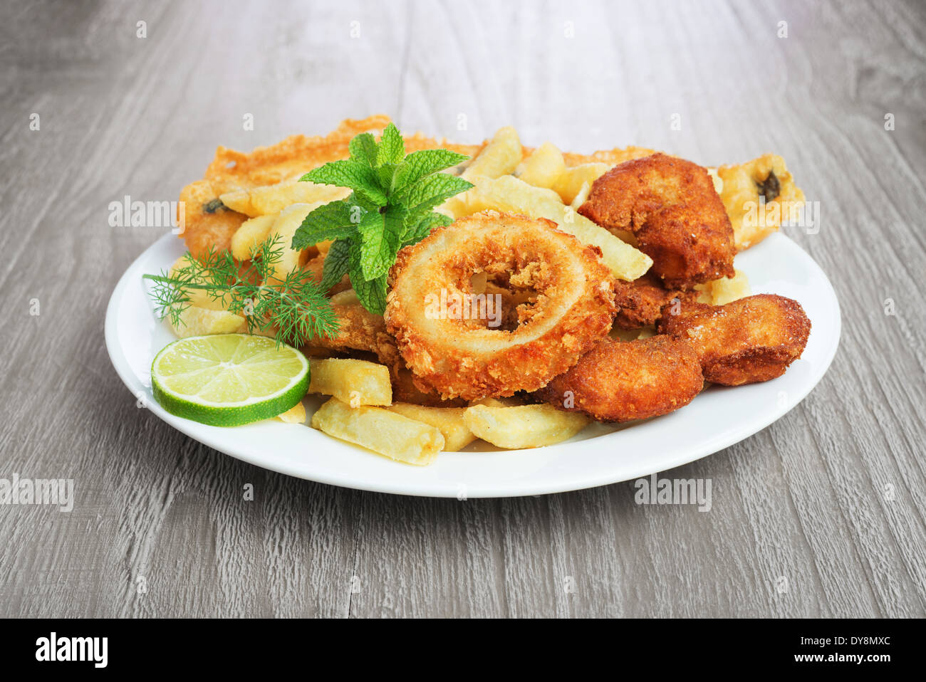 Fischgericht mit Panierter Fisch, Tintenfisch, Garnelen und Kartoffelchips auf Vintage Tisch Stockfoto