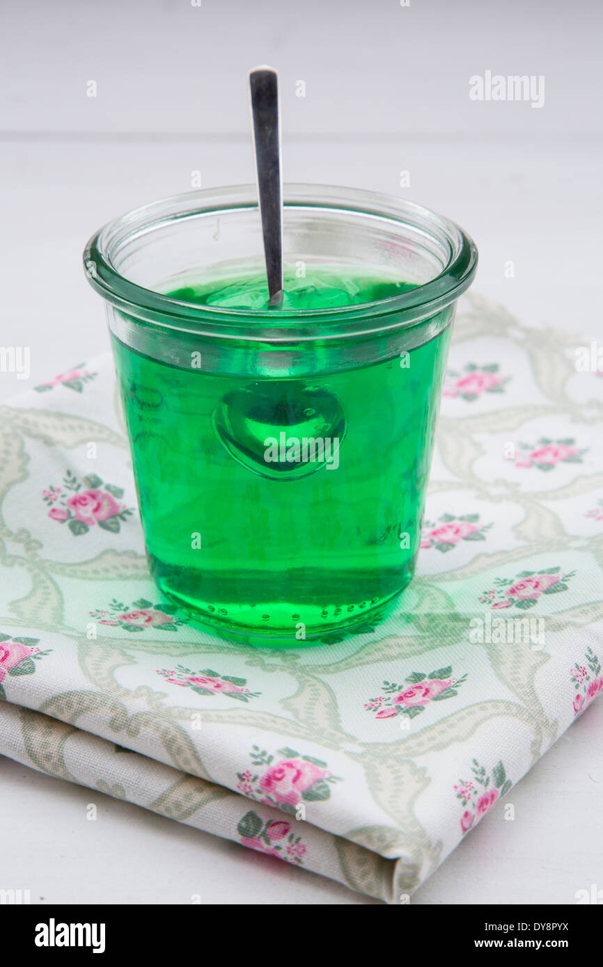 Glas mit Waldmeister-Gelee auf Tuch und weißem Grund bewahren Stockfoto
