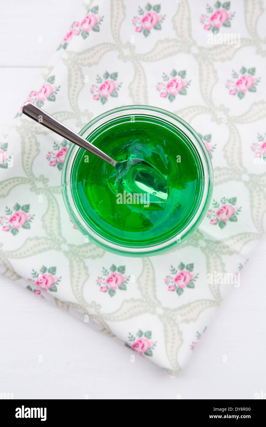 Glas mit Waldmeister-Gelee auf Tuch und weißem Grund, erhöhten Blick bewahren Stockfoto