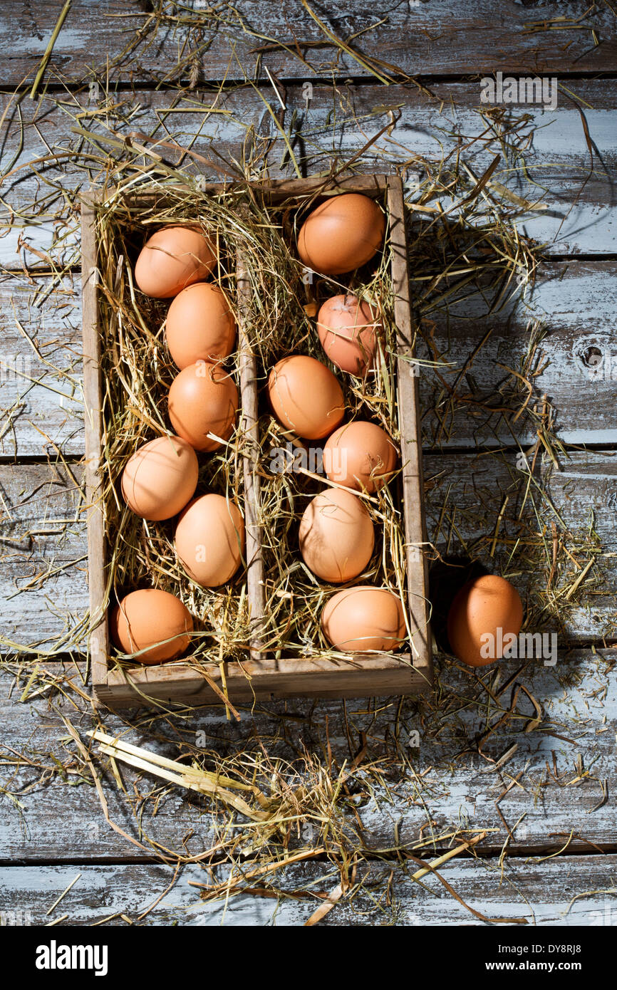 Holzkiste von braunen Eiern und Heu auf grauem Holztisch Stockfoto
