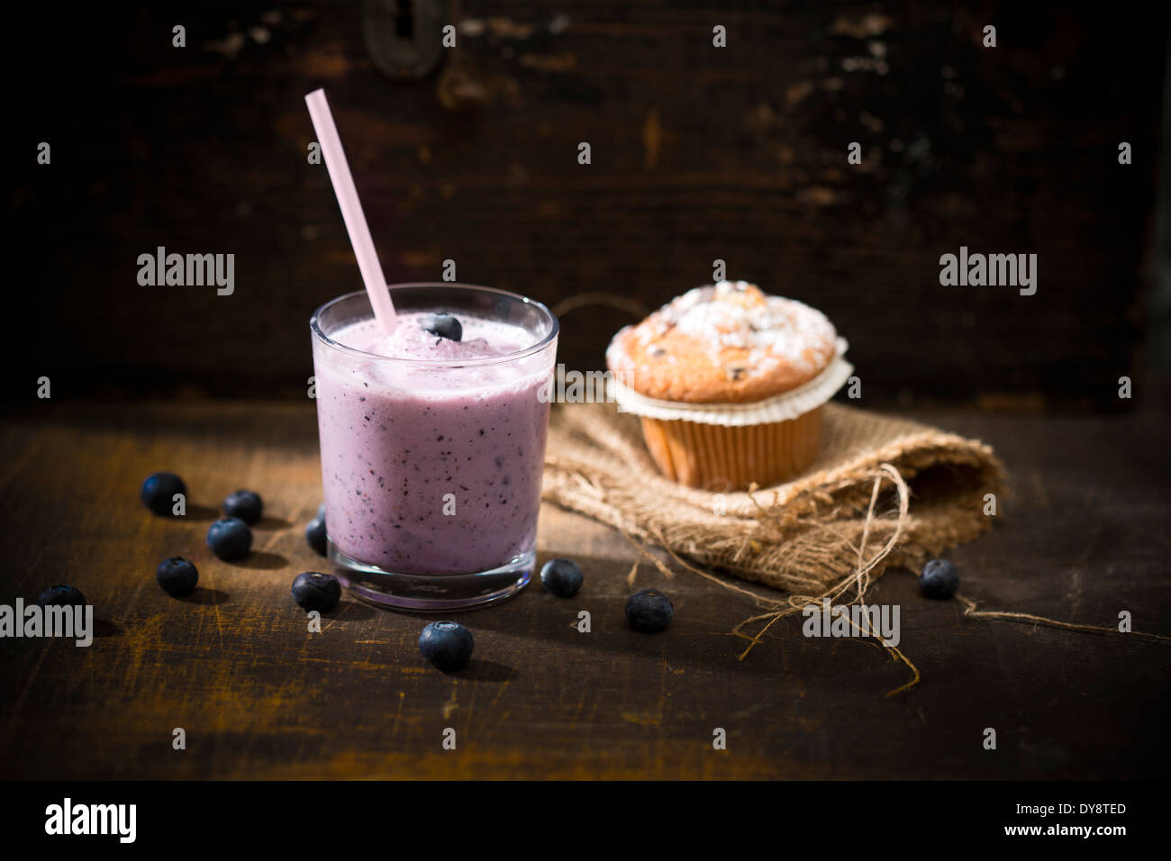 Glas Heidelbeeren Milchshake, Blueberry Muffin und Blaubeeren auf Holztisch Stockfoto
