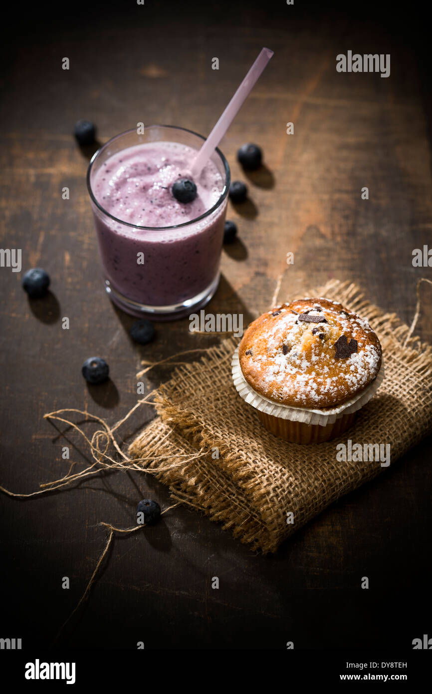 Glas Heidelbeeren Milchshake, Blueberry Muffin und Blaubeeren auf Holztisch, erhöht, Ansicht Stockfoto