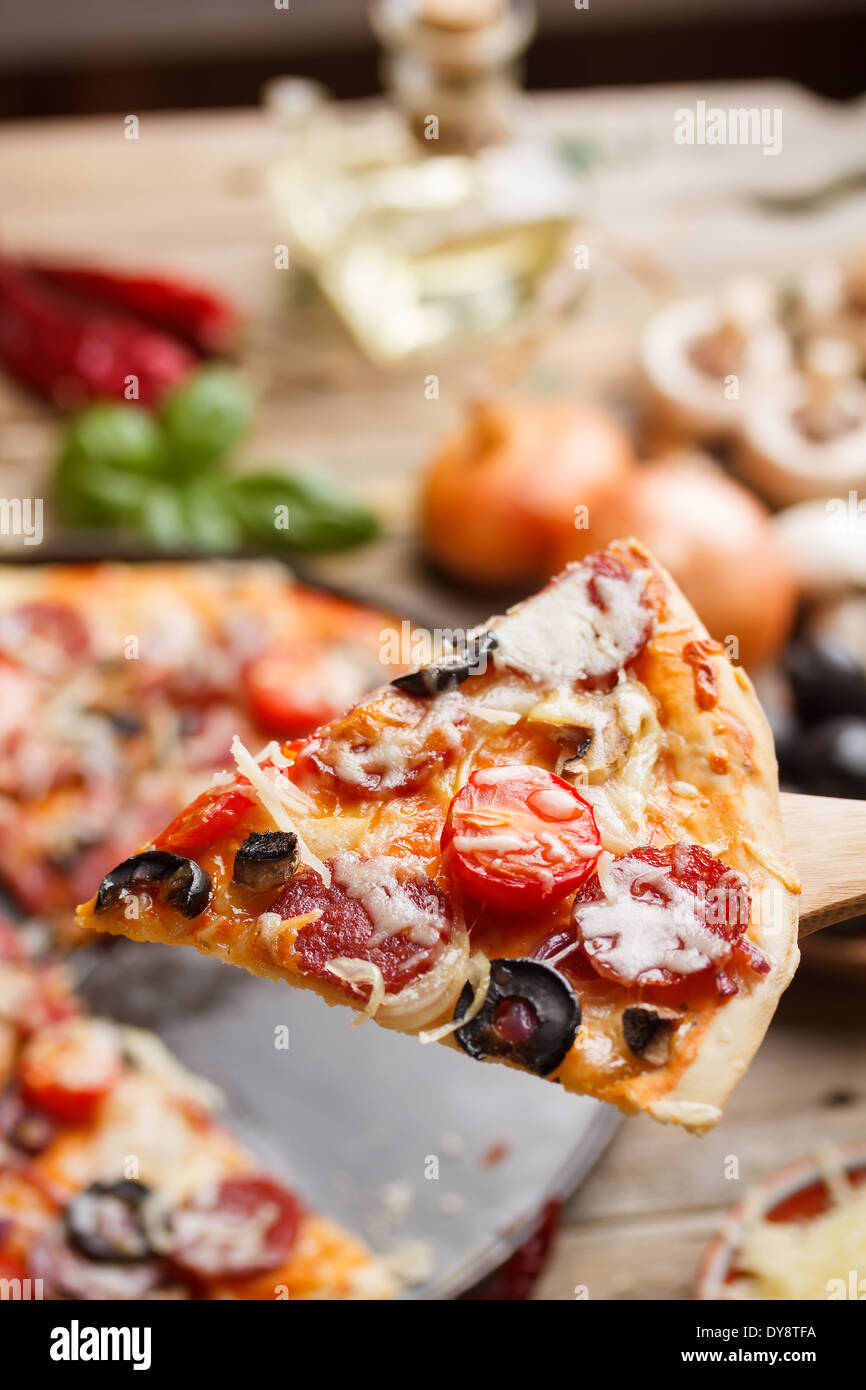 Rustikale Pizza mit Salami, Tomaten und Oliven Stockfoto
