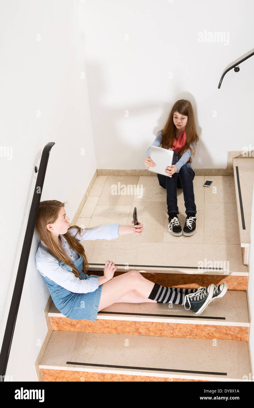 Zwei Mädchen im Teenageralter sitzen auf Treppen mit Smartphone und Tablet-digital Stockfoto