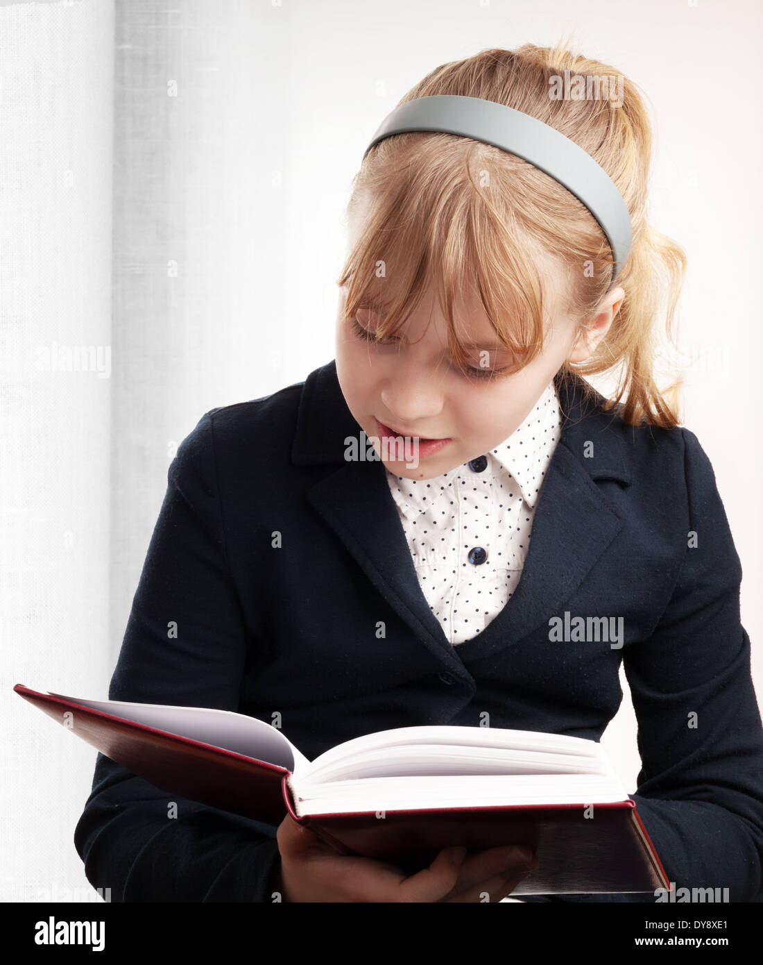 Closeup Portrait des blonden kaukasischen Schulmädchen Lesung Lehrbuch Stockfoto