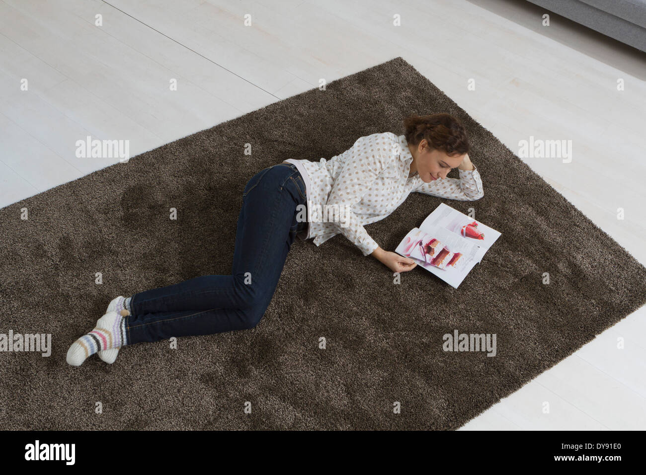 Frau liegt auf Teppich lesen Magazin Stockfoto