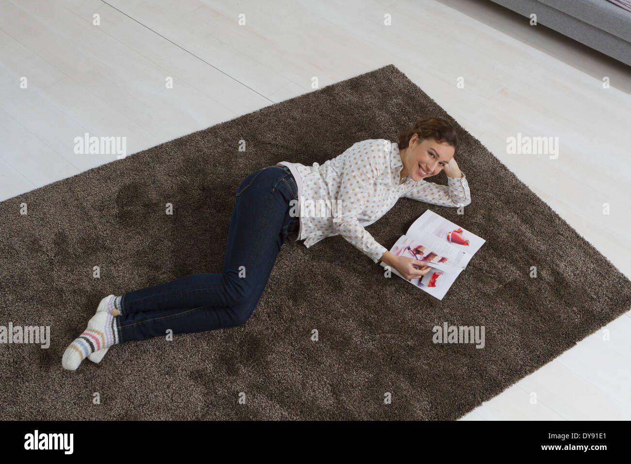 Frau liegt auf Teppich lesen Magazin Stockfoto