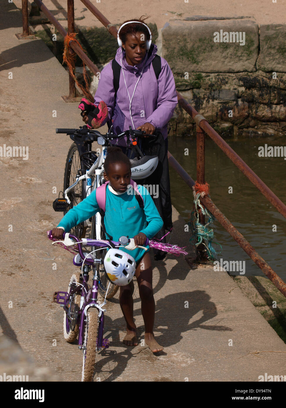 Schwarze britische Mutter und Tochter Fahrräder umstoßen Fußgängerbrücke, Bude, Cornwall, UK Stockfoto