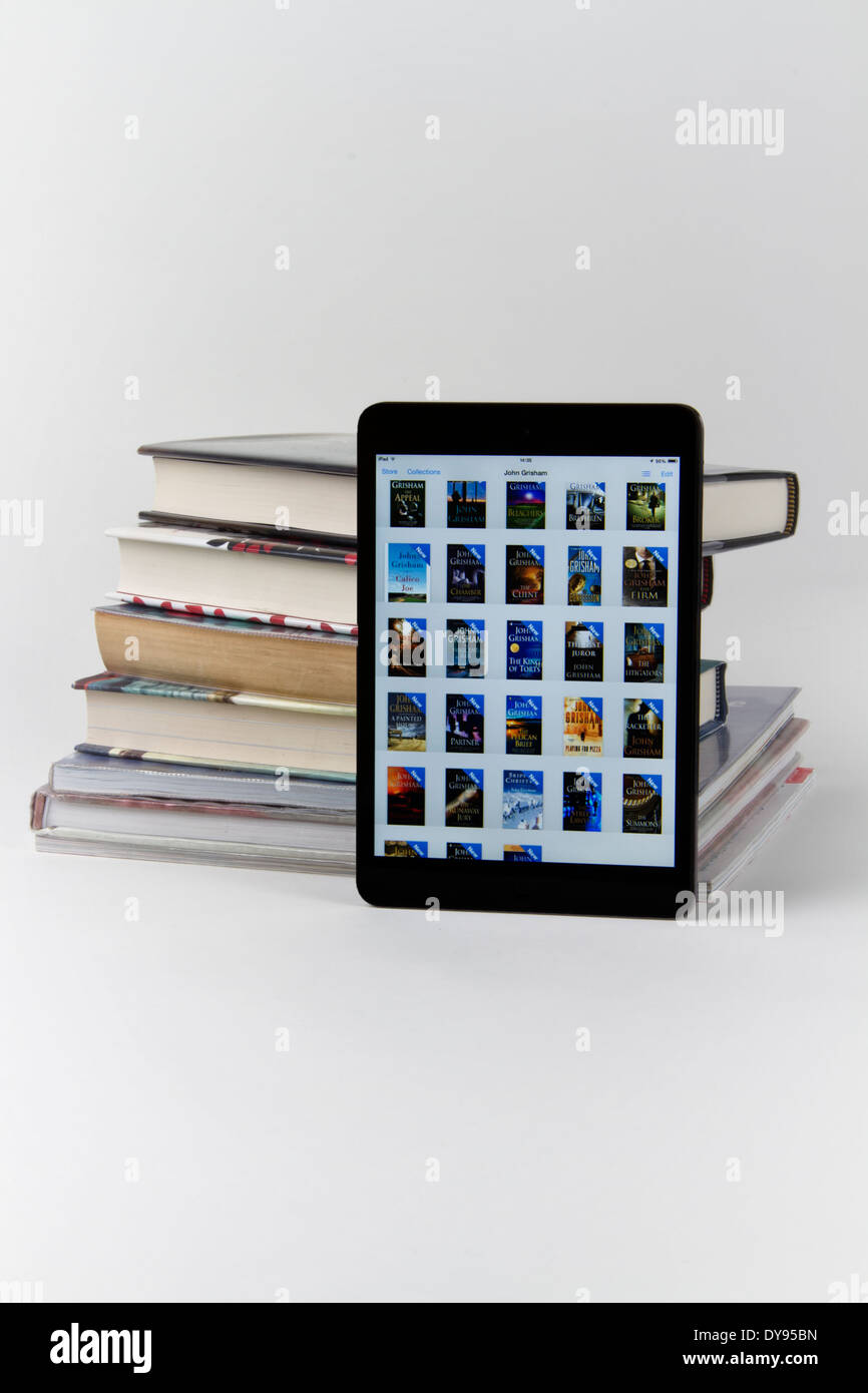 Apple iPad Mini Anzeige von Icons für 28 Bücher mit einem Stack von nur 6 bedrucktes Papier-Bücher Stockfoto
