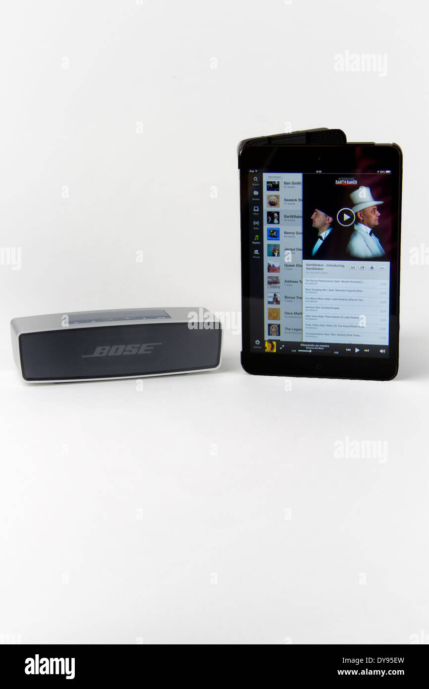 Apple iPad Mini läuft ein Musik-app und ein Bose tragbarer Bluetooth Lautsprecher Stockfoto